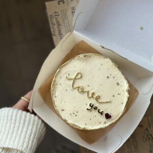 A person holding a box with a cake inside