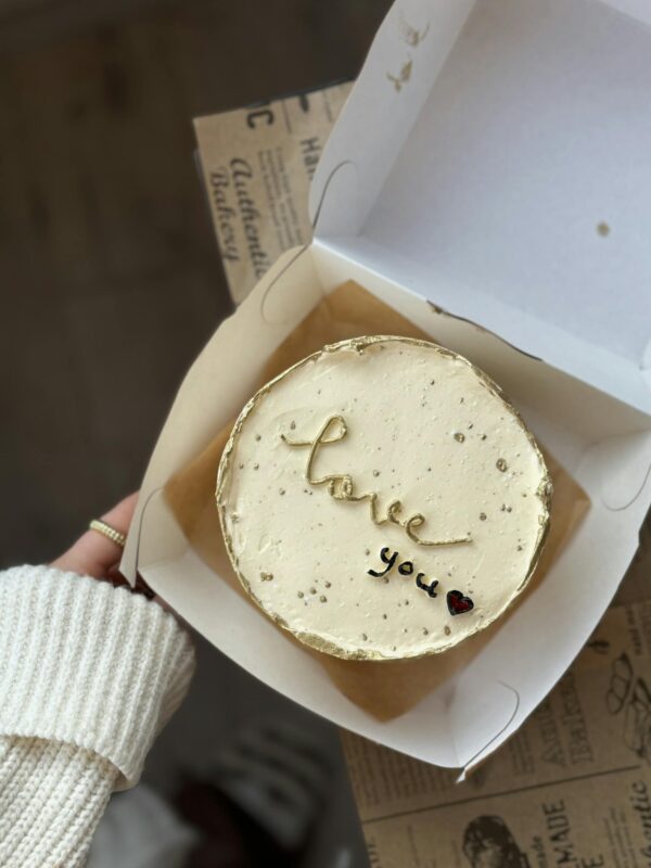 A person holding a box with a cake inside